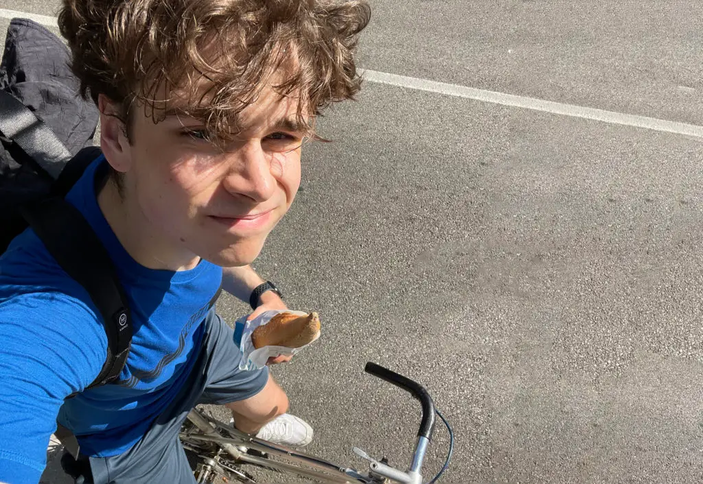 Junge auf Fahrrad mit Baguette in der Hand