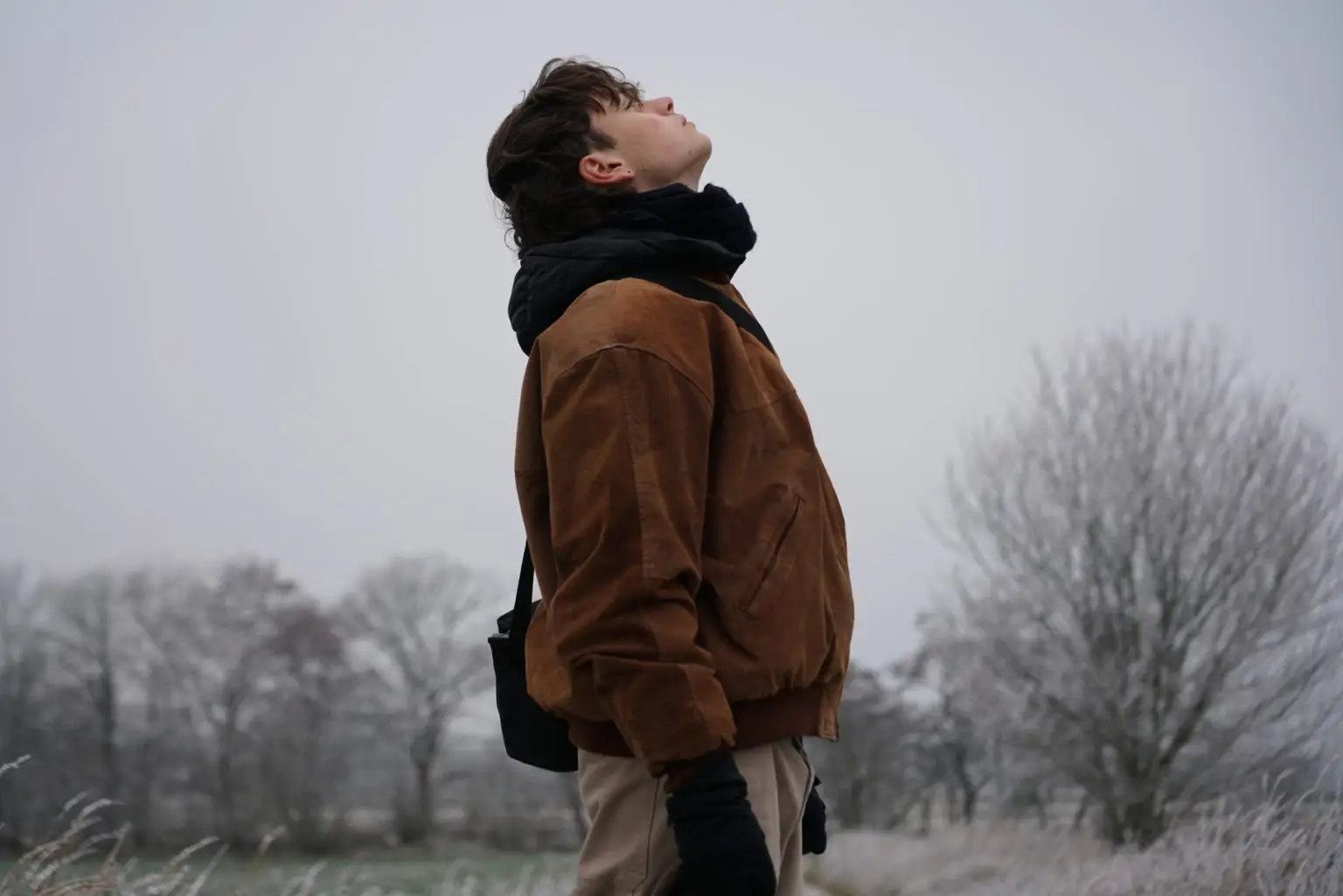 Junge in Winterlandschaft guckt in den Himmel